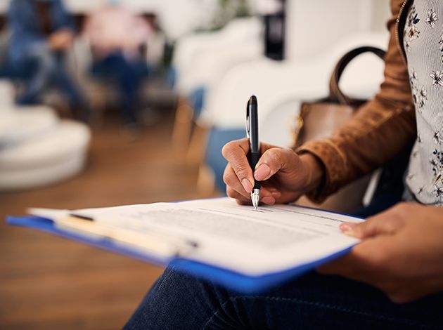 Person filling out paperwork on clipboard