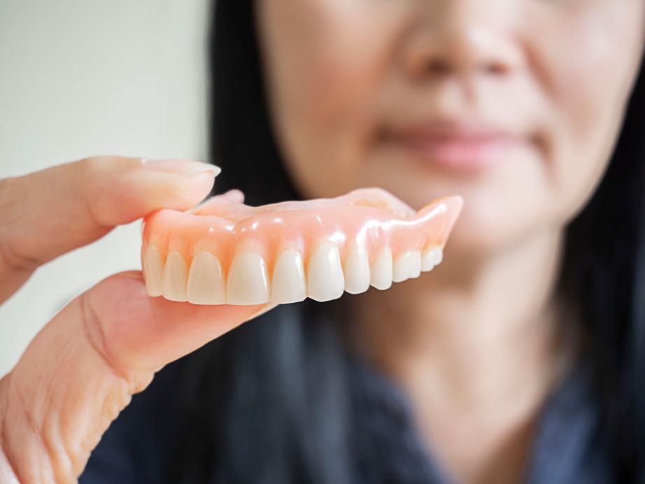 A woman holding a denture.